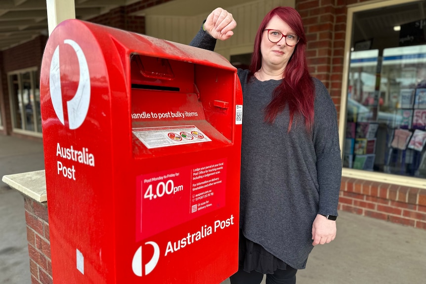 A person resting her arm on an Australia Post post box.