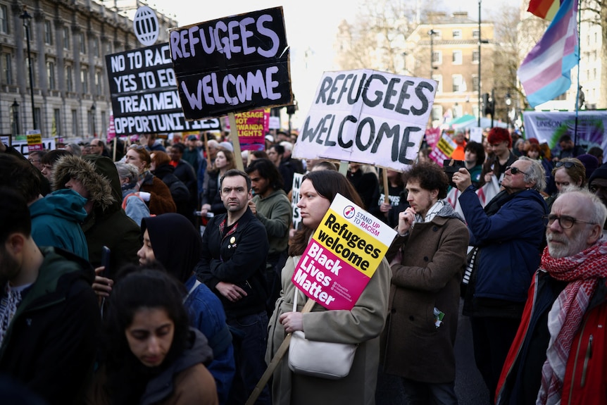 protesters holdings signs reading "refugees welcome" crowd Downing Street in London