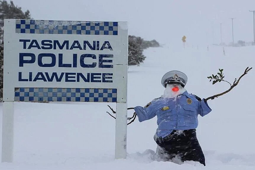 A snowman dressed in police uniform next to the Liawenee Police Station sign.