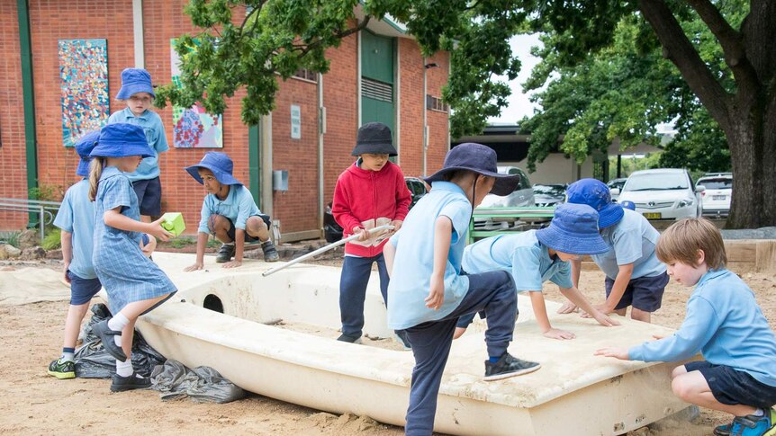 Students climbing over an old boat in the playground