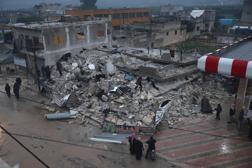 People search a collapsed building following an earthquake in Azmarin town, Idlib