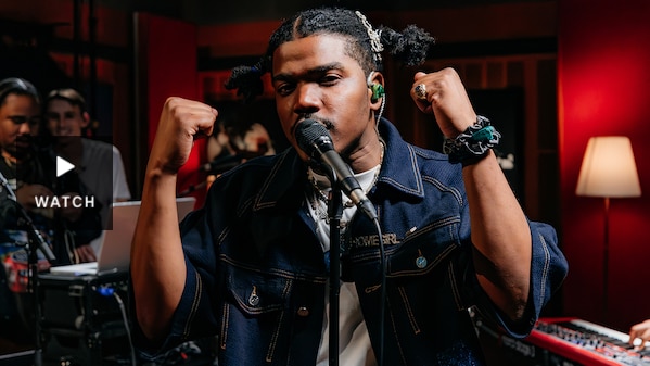 Smino looking at the camera with two fists next to his face in the Like A Version studio. Has Video.