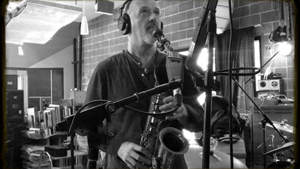 A monochrome photo of Ken Stubbs in the studio with an alto sax