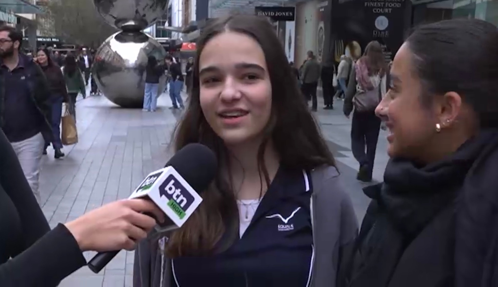 A teenage girl with long brown hair speaks into a BTN microphone.