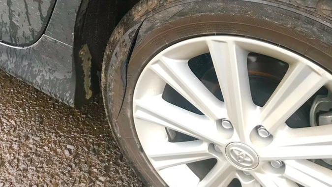 A close-up of car wheel, showing that the tyre has been slashed