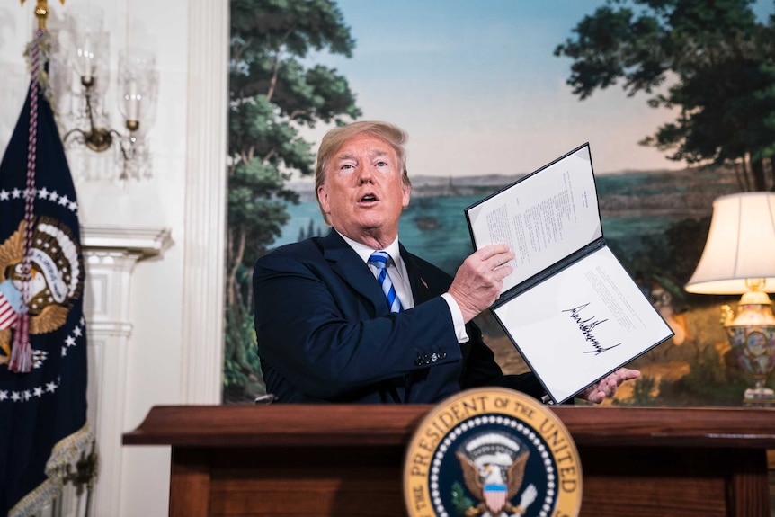 US president donald trump holds a document where he has signed to withdraw the US from the Iran nuclear deal.