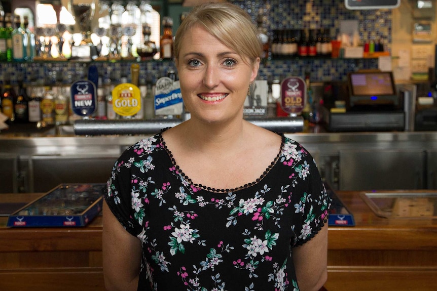 Image of female publican standing in front of the public bar.