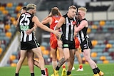 An AFL player gets a pat on the head and a tap on the arm as he walks back after kicking a goal.