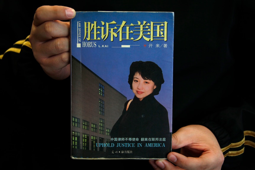 A pair of hands holds up a book with a woman on the cover with Chinese writing across the top