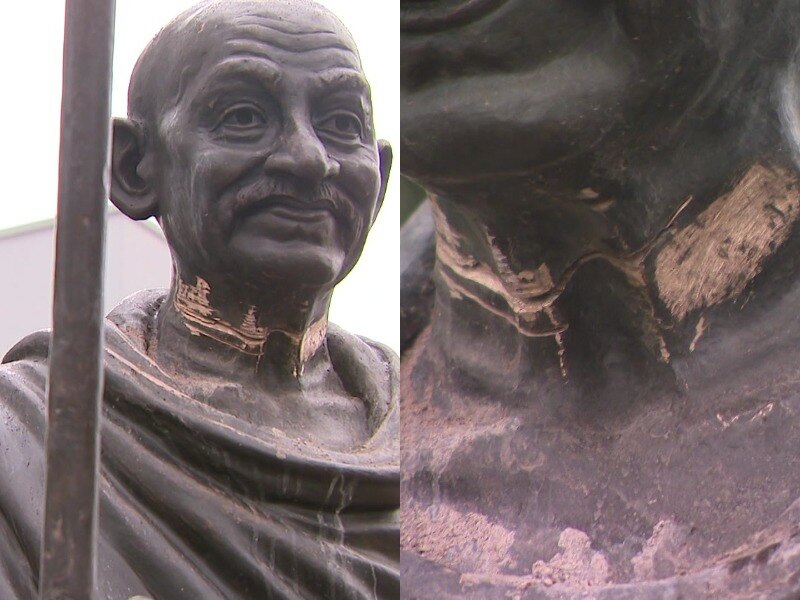 A statue of Mahatma Gandhi with marks on its neck.