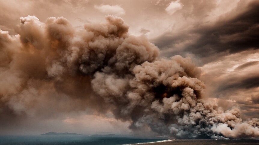 Smoke billows out from bushfires over the beach and townships of Forster-Tuncurry in New South Wales