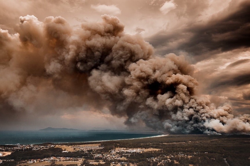 Smoke billows out from bushfires over the beach and townships of Forster-Tuncurry in New South Wales