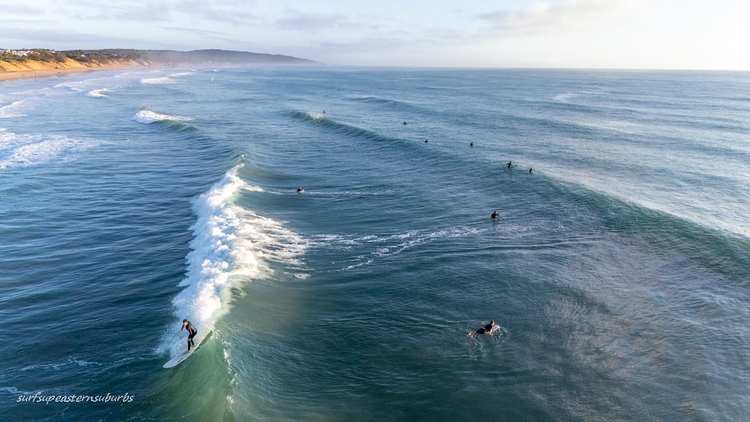 Una vista aérea de una playa con un surfista montando una ola.
