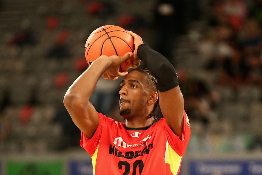 A basketball player holds the ball ready to shoot.