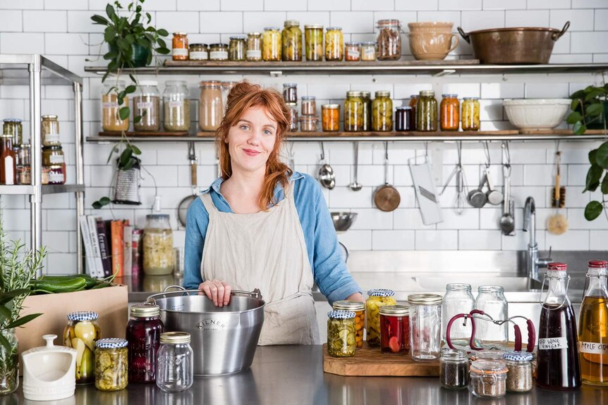 Cornersmith Cafe's Alex Elliot Howery stands in her commercial kitchen behind a bench full of stocks, pickles and preserves