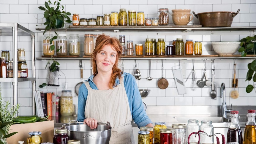 Alex Elliot Howery stands in her commercial kitchen behind a bench full of stocks, pickles and preserves that reduce food waste.