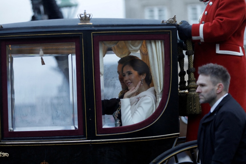 A woman waves from a carriage 