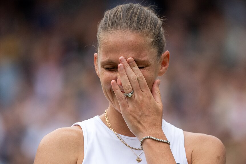 Karolina Pliskova holds her hand to her face to cover tears.
