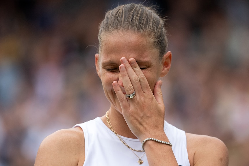 Karolina Pliskova holds her hand to her face to cover tears.