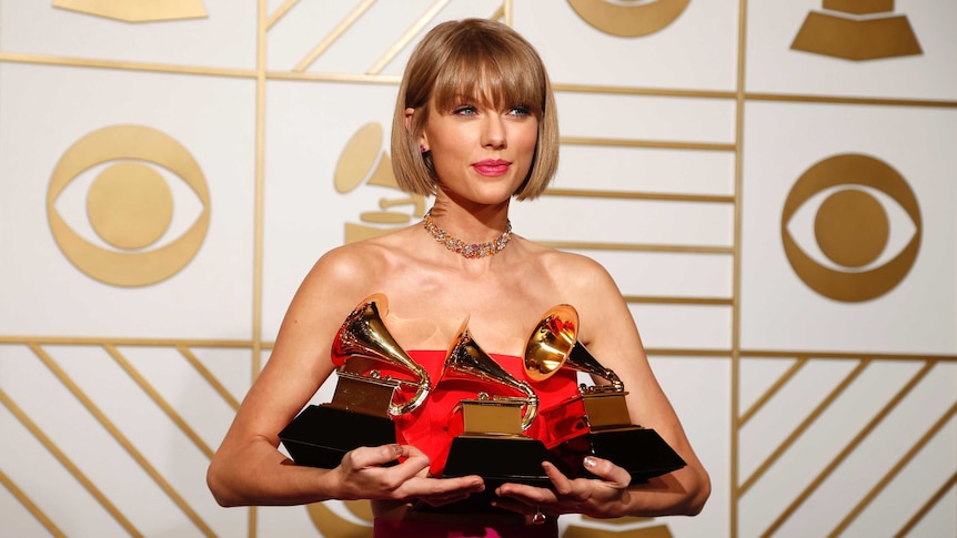 Taylor Swift poses with her three Grammy awards at the 2016 event.