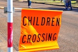 A generic photo of a children crossing sign near a school.