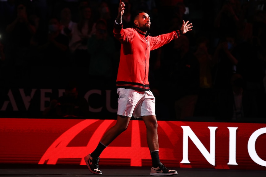 Nick Kyrgios raises his arms to the crowd as a red light welcomes him to the court