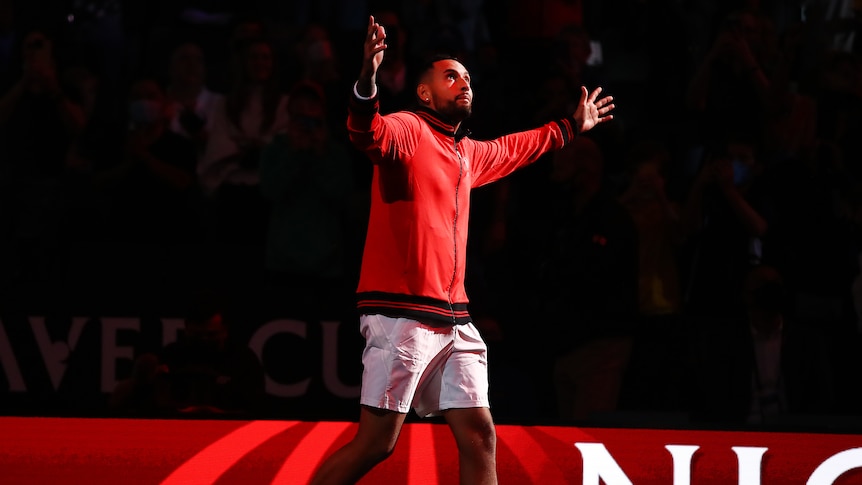 Nick Kyrgios raises his arms to the crowd as a red light welcomes him to the court
