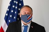 Mike Pompeo in a face mask with a US flag behind him