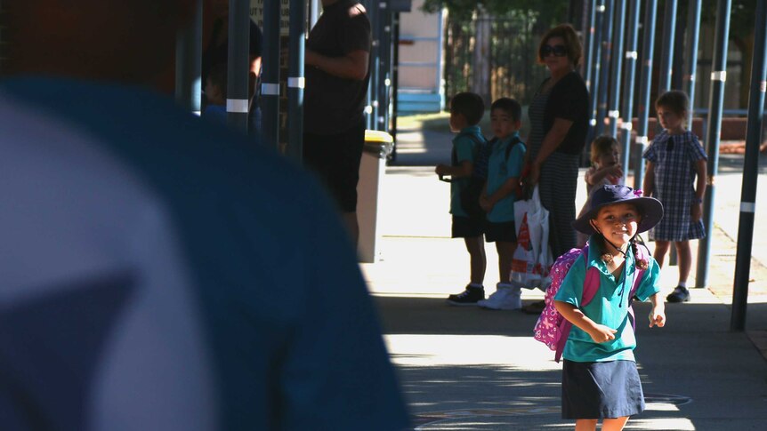 Zoe turns back and smiles at her parents as she runs off to start her first day of kindergarten.