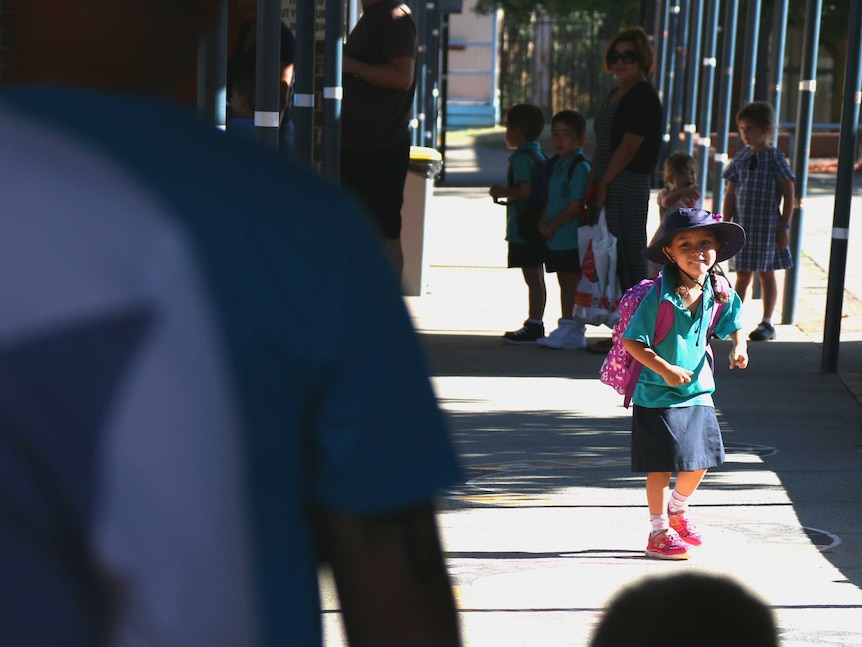 Zoe turns back and smiles at her parents as she runs off to start her first day of kindergarten.