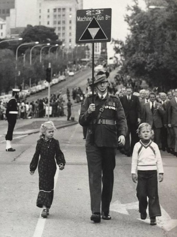 Norvyn Wallace 'Bluey' Stevens marching with a sign in his hand, with two children standing beside him