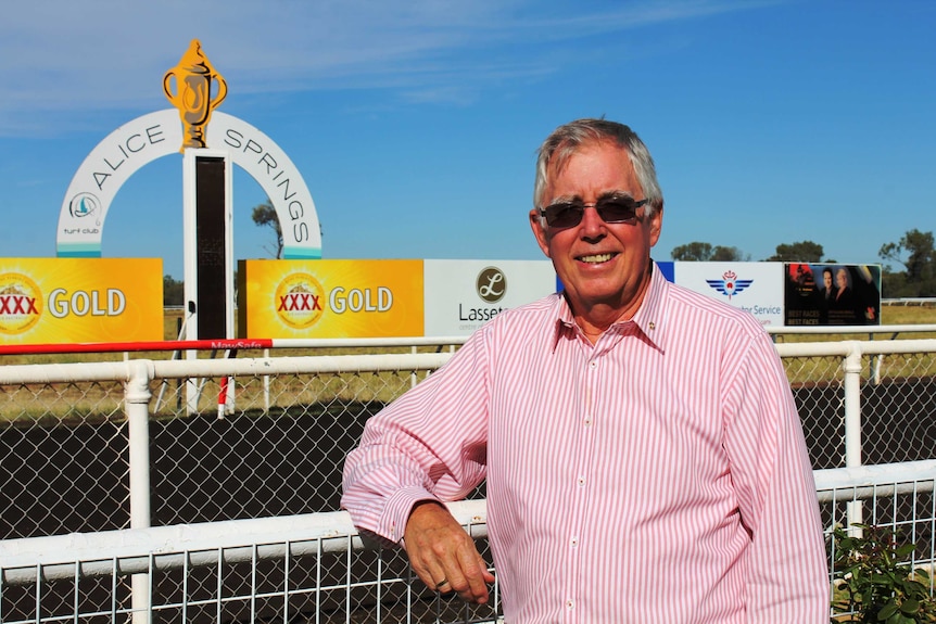 a man standing at the finish line at the Alice Springs race track