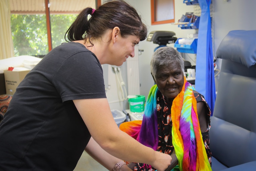 A nurse assists a patient on a dialysis chair.