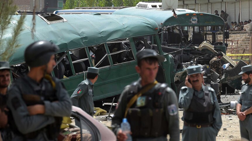 Afghan security personnel gather near the wreckage of buses.