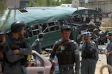 Afghan security personnel gather near the wreckage of buses.