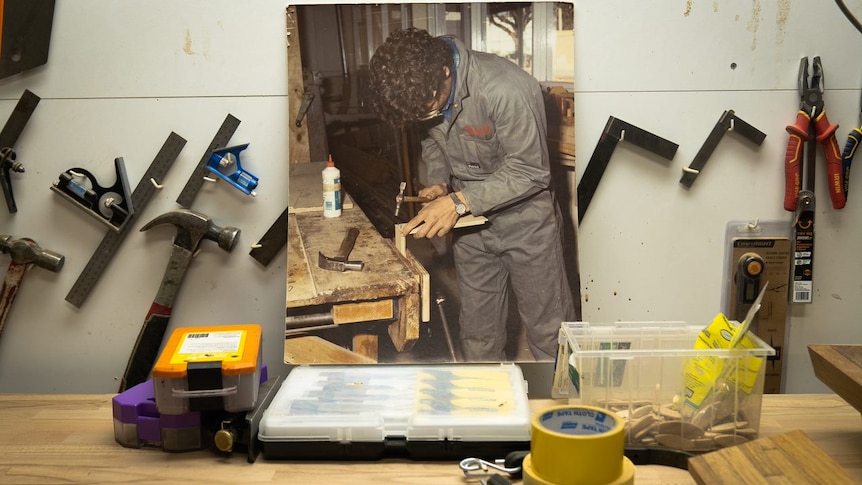 A printed photo of a man at a workbench, seen on a workbench.