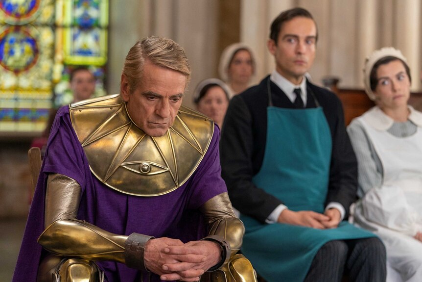 Jeremy Irons dressed as superhero Ozymandias, looking dejected in a courtroom in the TV series Watchmen