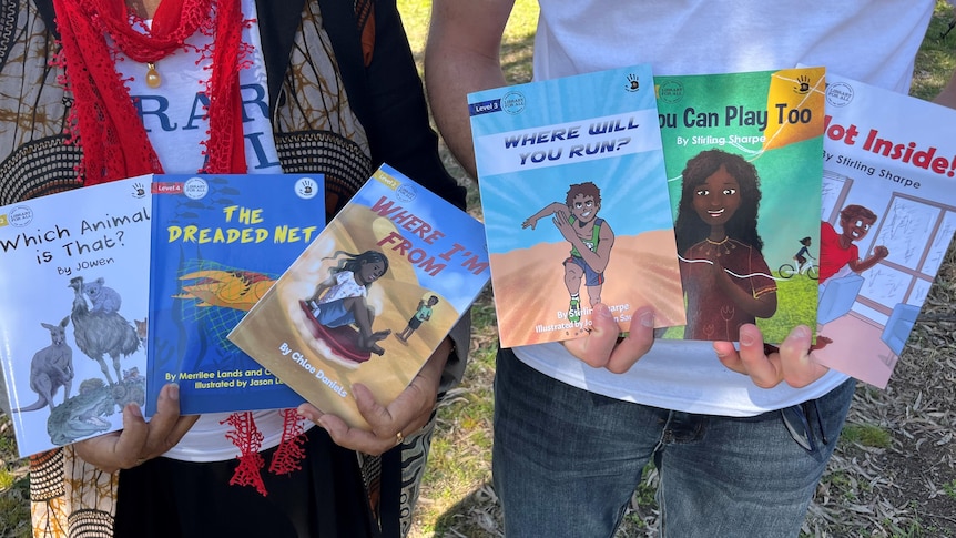 A woman holds three childrens books and a man holds three story books 