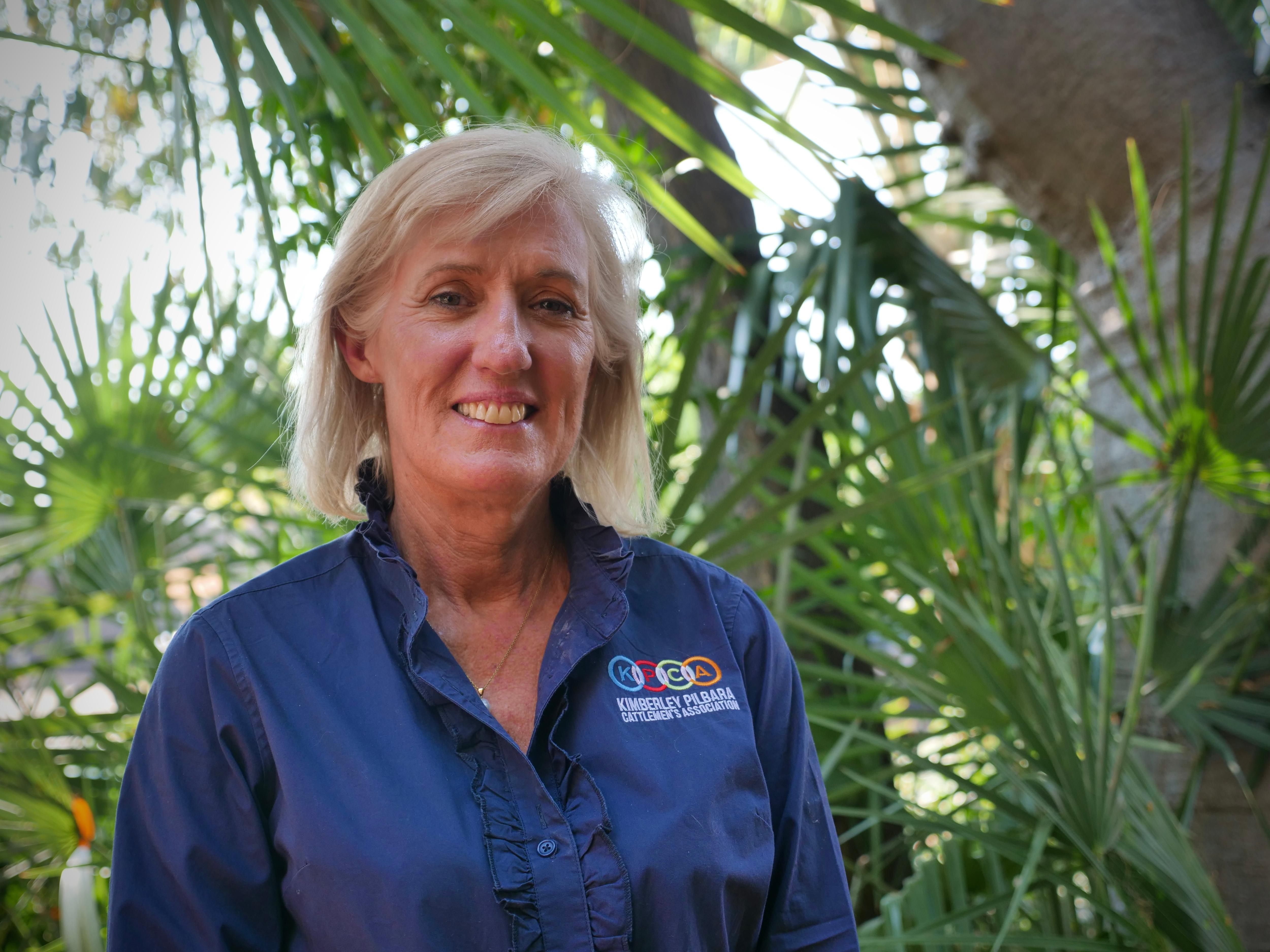 woman in KPCA-branded shirt stands in front of tree smiling at camera