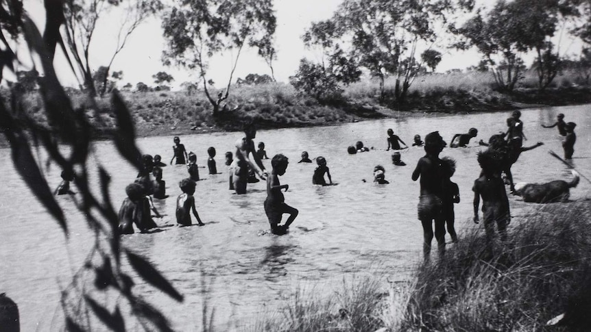 An archival photo showing children swimming in a creek in central Australia.