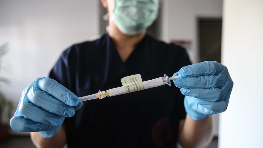 A Turkish health care worker holds an injection syringe of the Pfizer vaccine