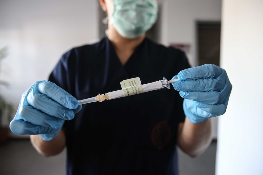 A Turkish health care worker holds an injection syringe of the Pfizer vaccine