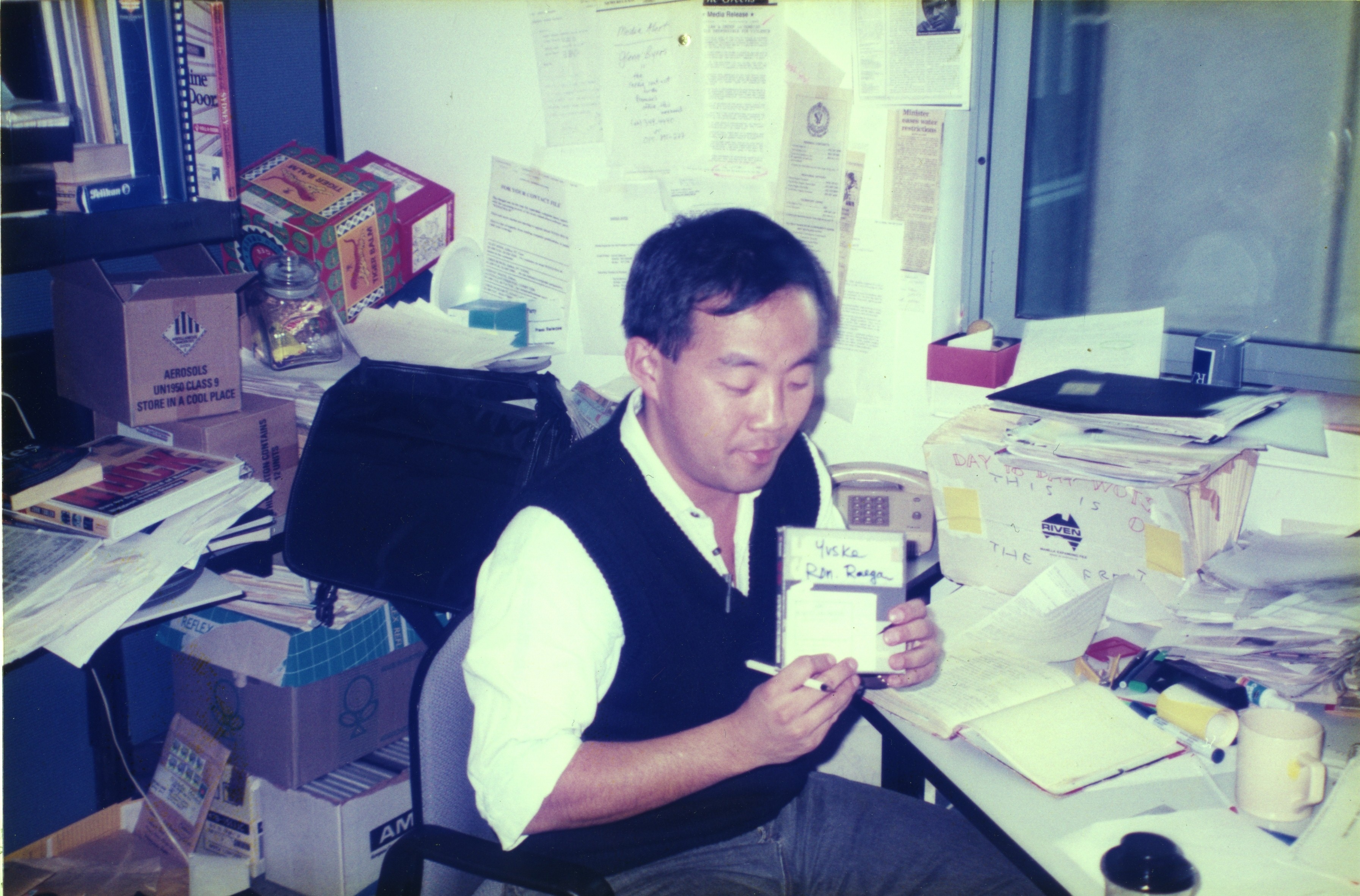 a man holds a tape while seated at a desk