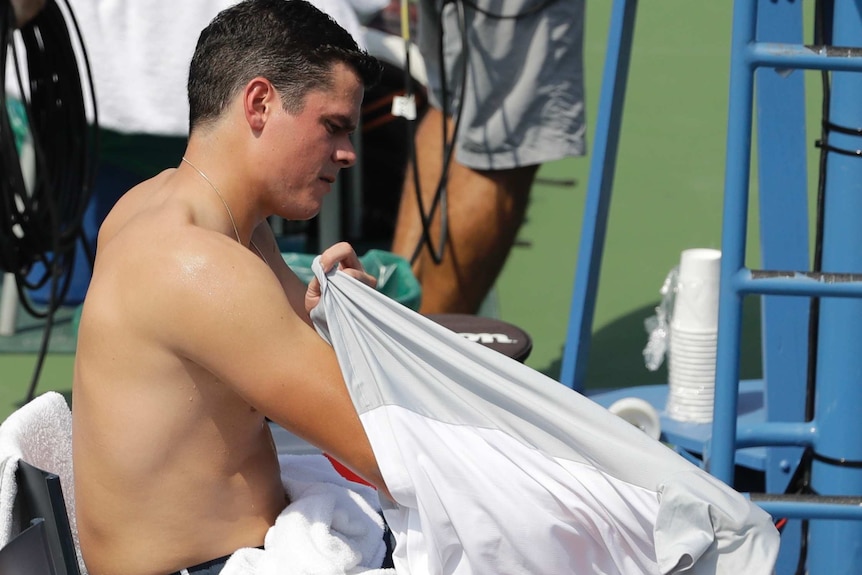 Milos Raonic changes his shirt during a changeover in his match against Gilles Simon.