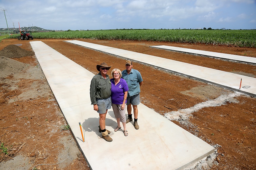 Kelvin, Helen and Jason Griffin standing on the end of a concrete slab in a field of cane.
