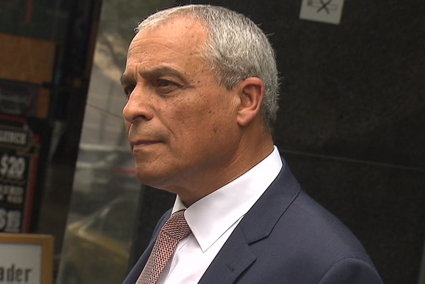 Charlie Bezzina, dressed in a suit and tie, stands outside the building in which an IBAC hearing was being held.