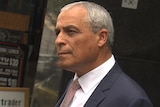 Charlie Bezzina, dressed in a suit and tie, stands outside the building in which an IBAC hearing was being held.