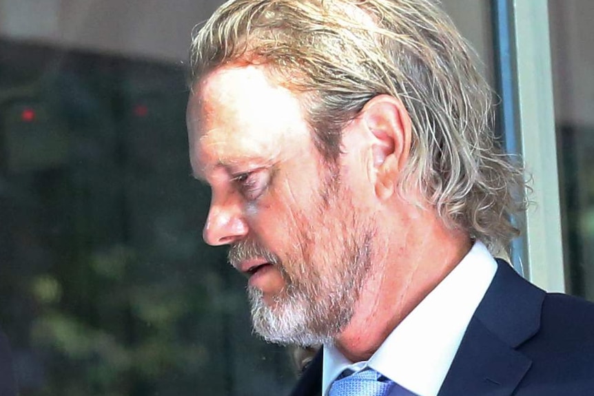 Craig McLachlan arrives at the Melbourne Magistrates' Court wearing a dark blue suit jacket and tie.