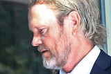 Craig McLachlan arrives at the Melbourne Magistrates' Court wearing a dark blue suit jacket and tie.
