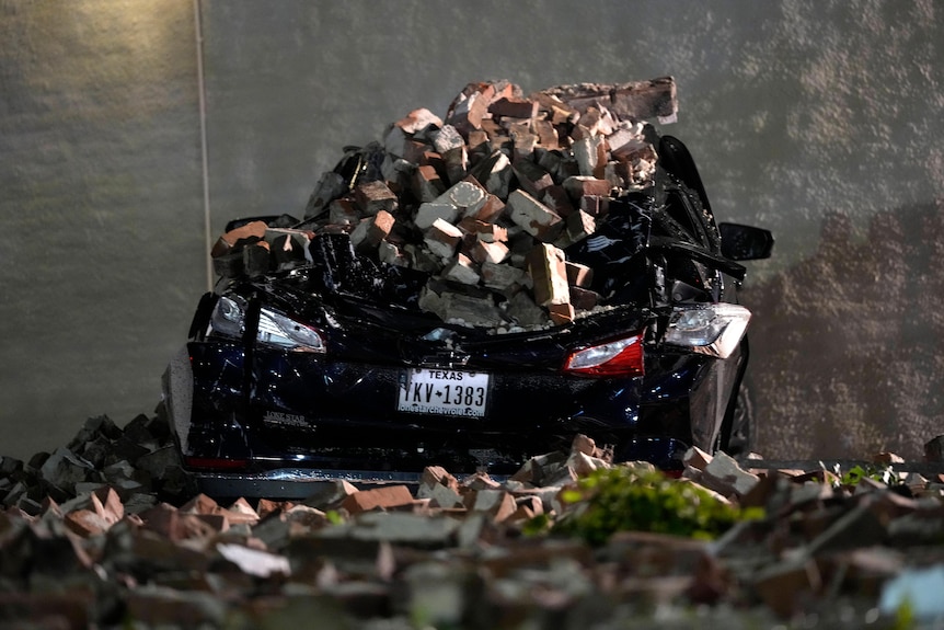 a car covered in fallen bricks